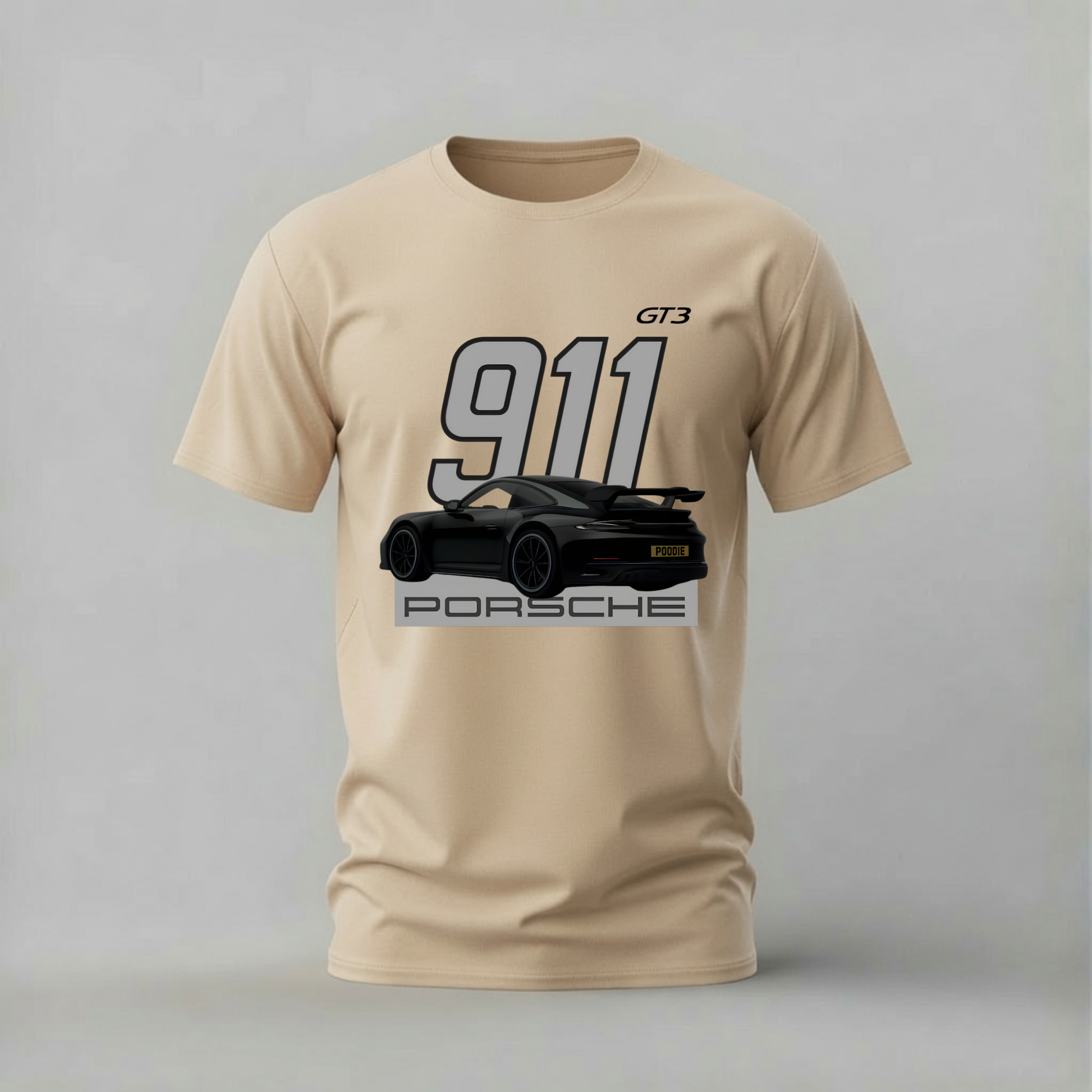 A beige short-sleeve t-shirt featuring a graphic print of a black Porsche 911 sports car with '911', 'GT3', and 'PORSCHE' text on the front, displayed against a neutral gray background.