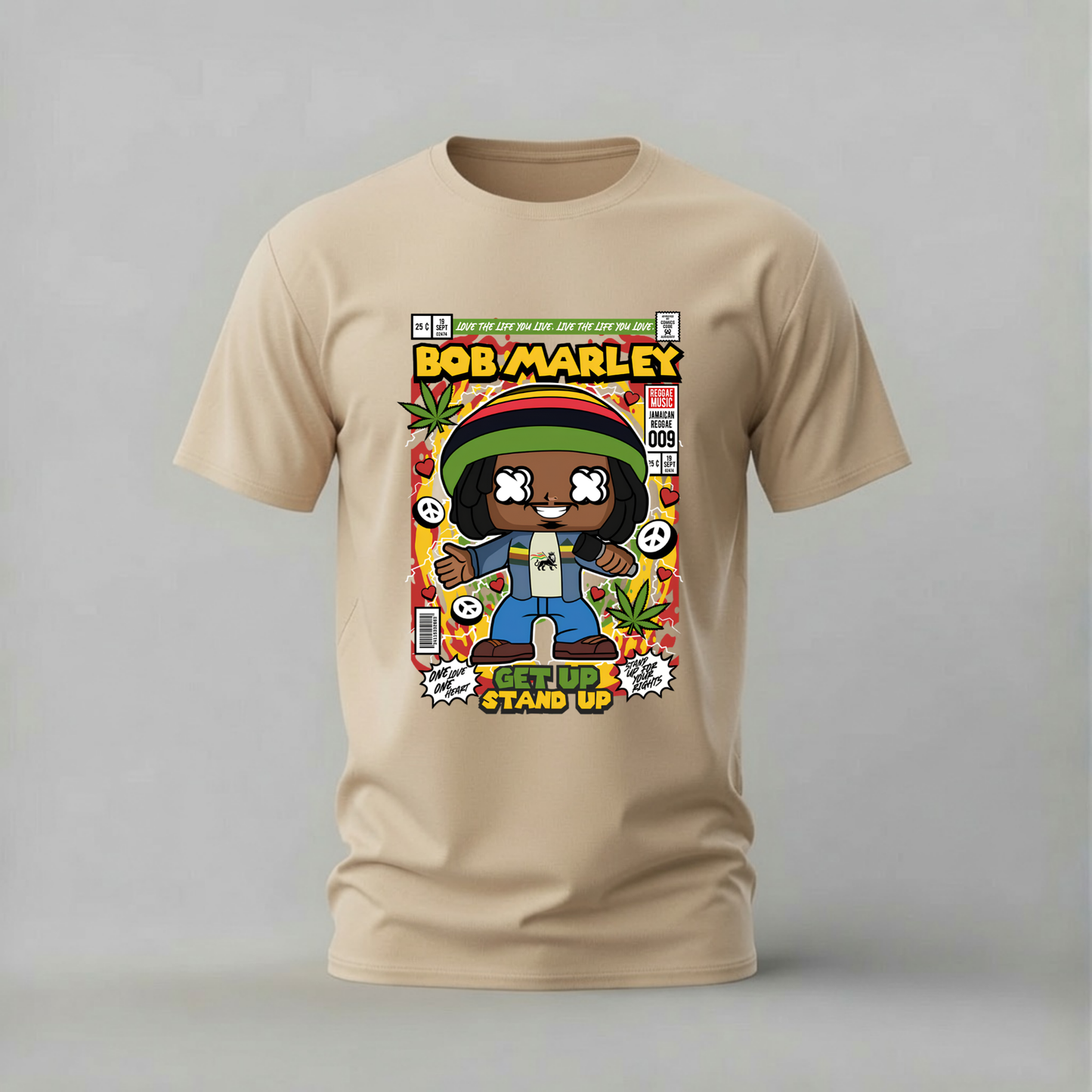 A beige short-sleeve t-shirt with a colorful graphic print of a cartoon-style Bob Marley comic book cover, displayed on a neutral gray background.