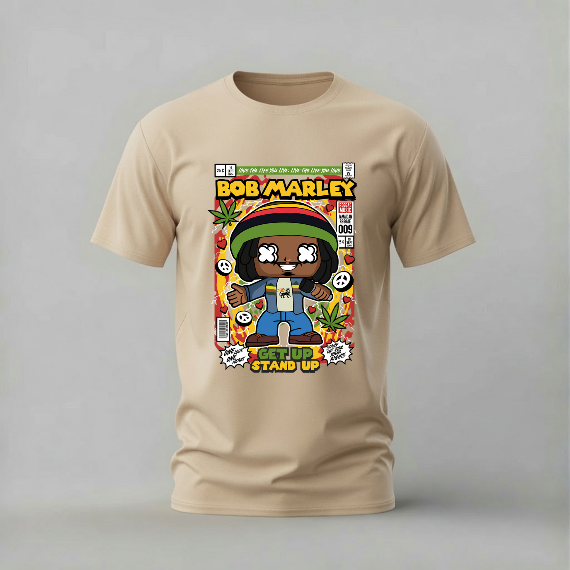 A beige short-sleeve t-shirt with a colorful graphic print of a cartoon-style Bob Marley comic book cover, displayed on a neutral gray background.