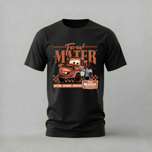A black short-sleeve crewneck t-shirt featuring a graphic print of the character Mater from Disney's Cars, with retro-style text reading 'Tow Mater' and 'Anytime - Anywhere - Anyplace' on a light gray background.