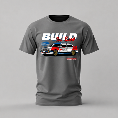 A dark gray crewneck t-shirt featuring a graphic print of a red, white, and blue classic race car with the text 'BUILD For Good' and 'E3 POWER' on a light gray background.