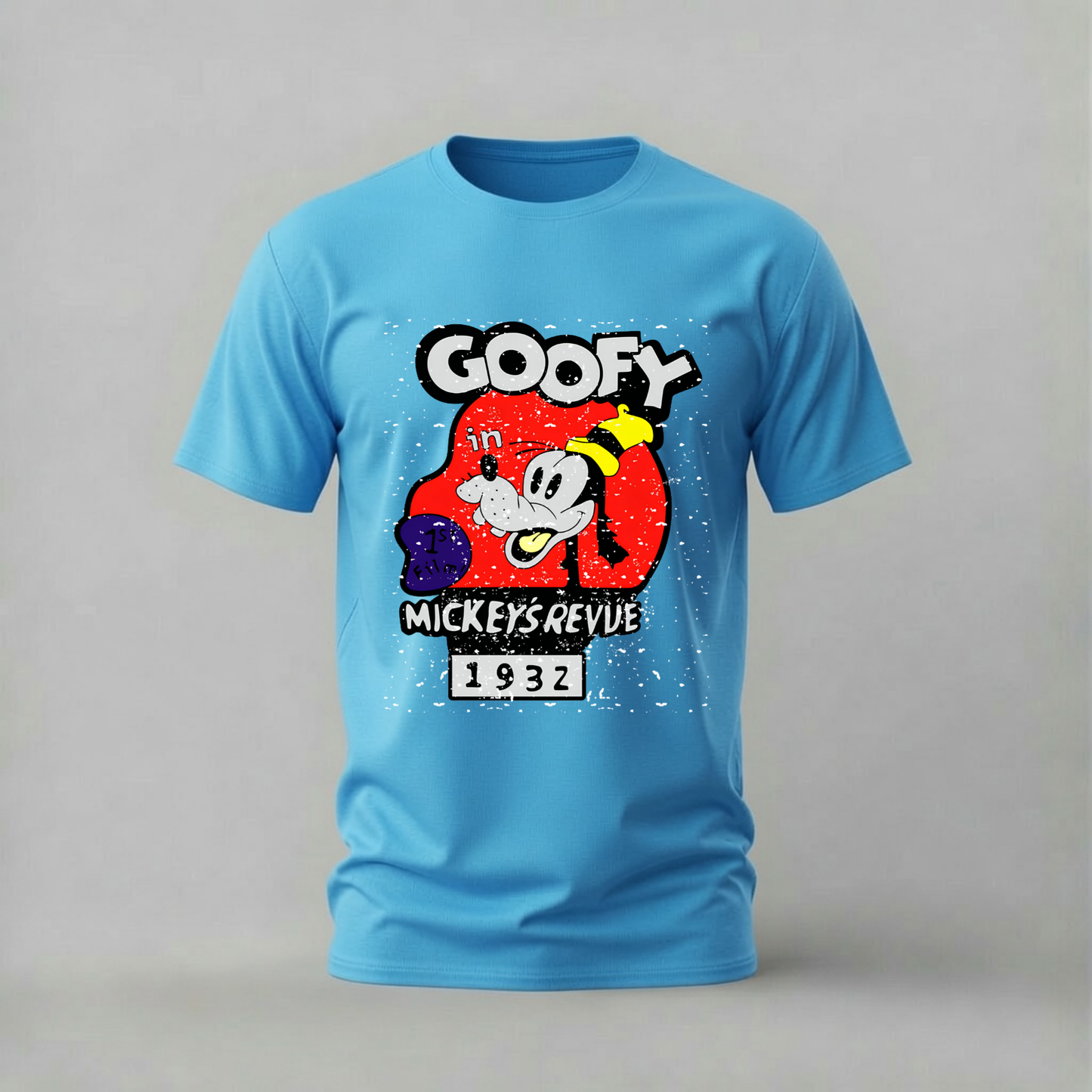 A light blue short-sleeve t-shirt featuring a vintage-style graphic print of Goofy from Mickey's Revue 1932 on the front, set against a neutral gray background.