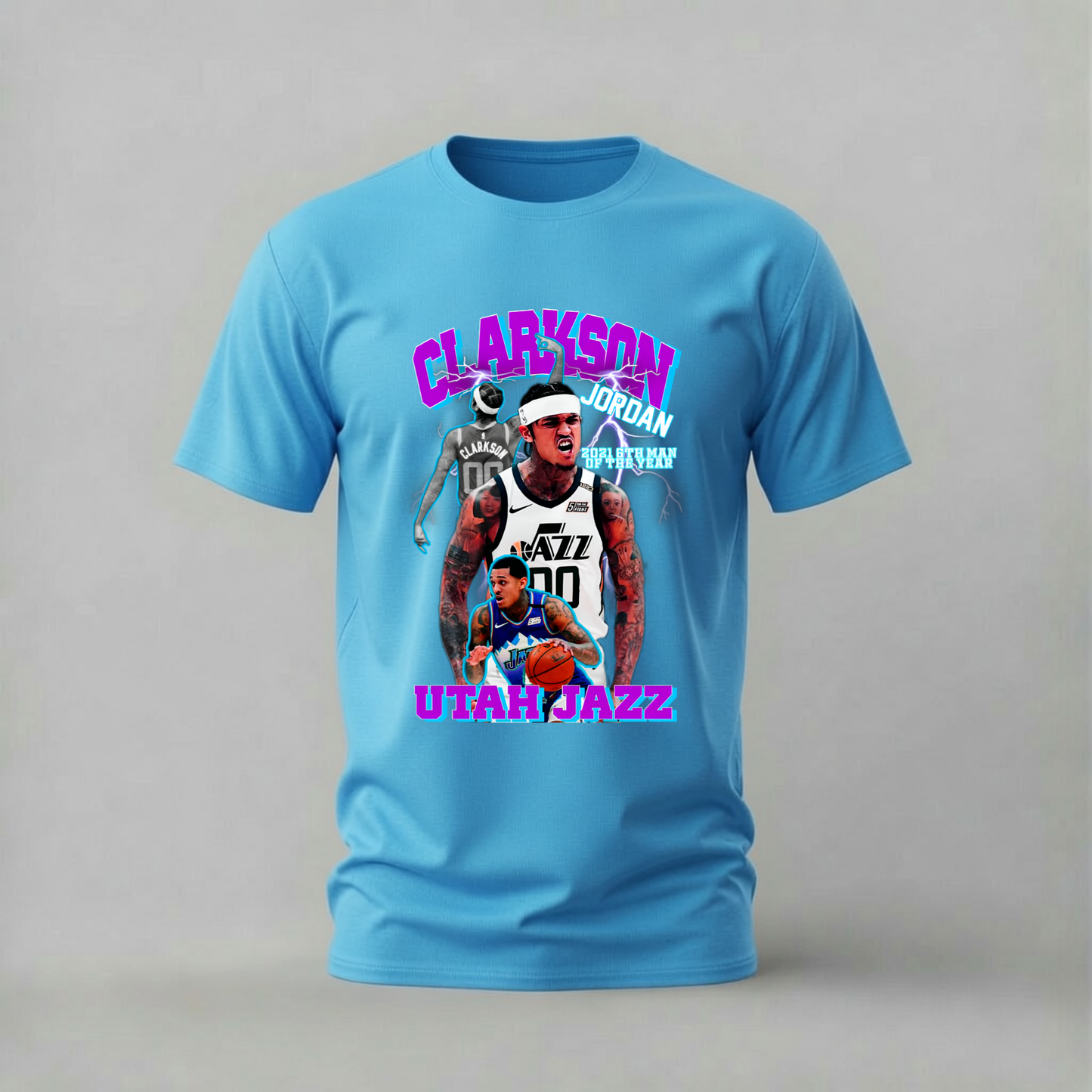 A light blue short-sleeve t-shirt with a colorful graphic print of basketball player Jordan Clarkson and the Utah Jazz, displayed on a neutral gray background.