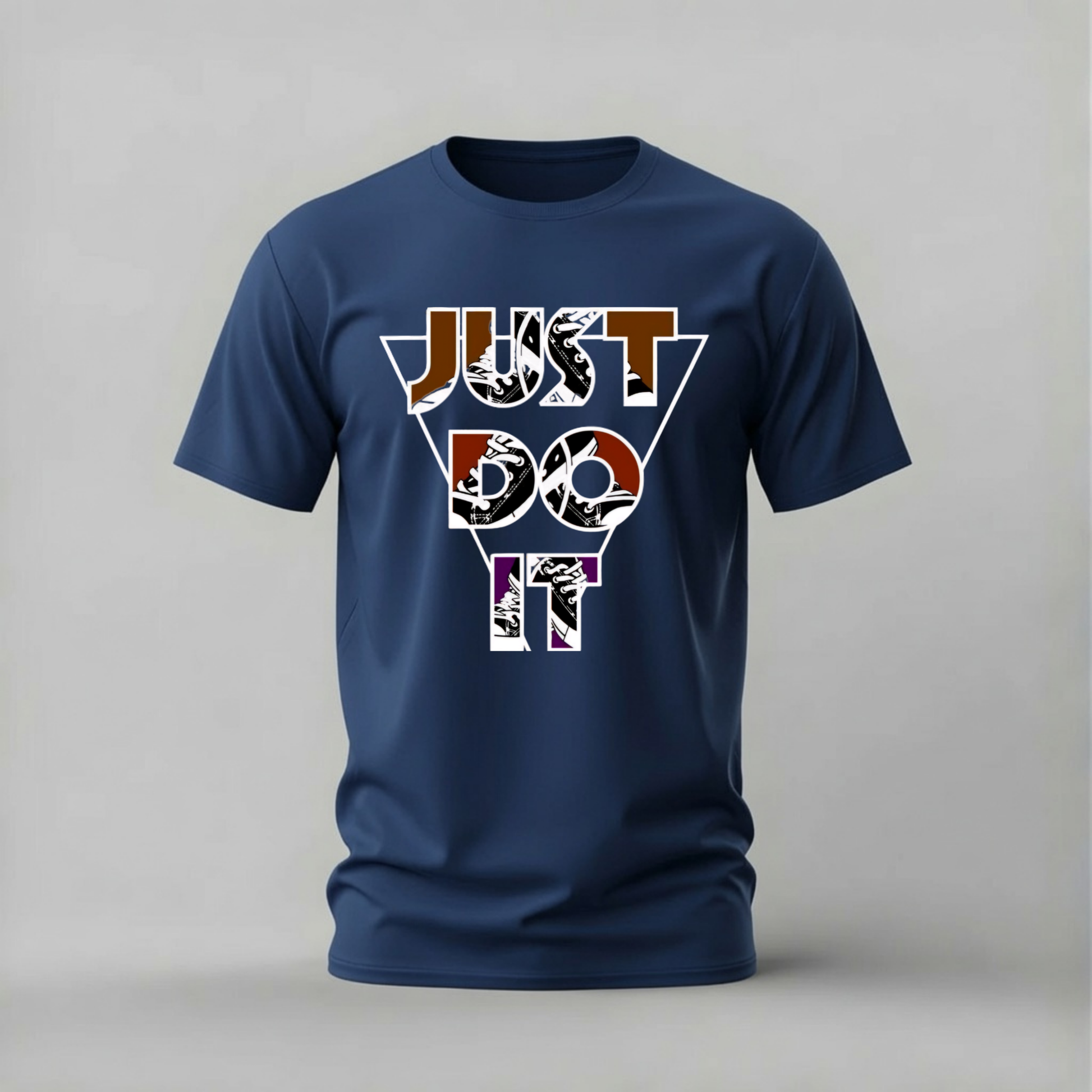 A navy blue short-sleeve t-shirt with a graphic on the chest reading 'JUST DO IT' in a geometric, collage-style font with black, white, orange, and purple details, displayed on a neutral gray background.